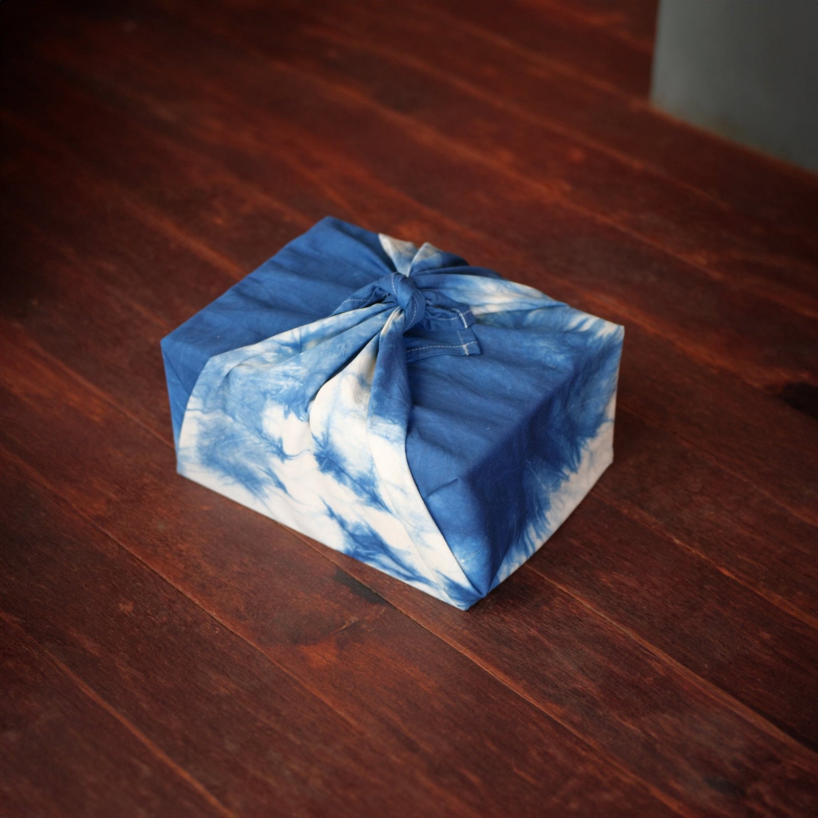 A furoshiki wrapping cloth in hand-dyed indigo, knotted around a gift.