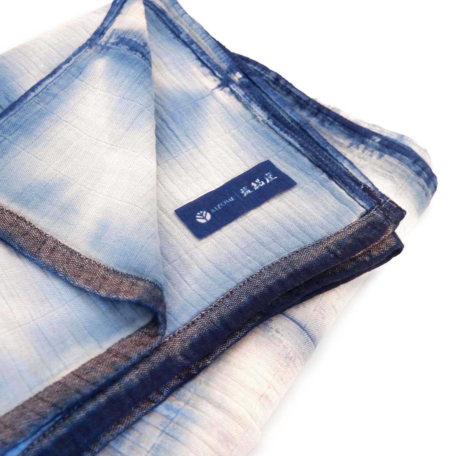 The Yūgen bed throw in hand-dyed indigo, draped across a bed.